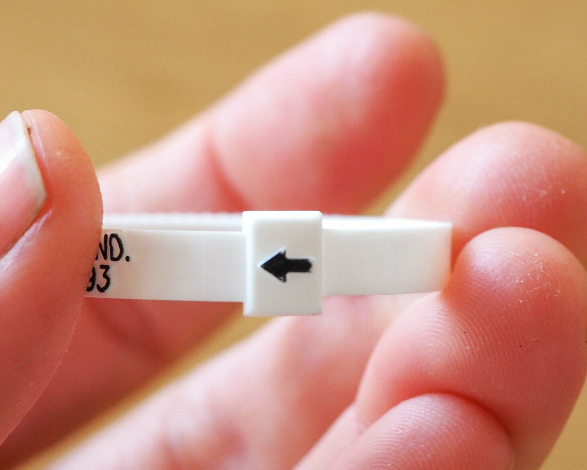 Close-up of a hand holding a white plastic ring sizing kit.