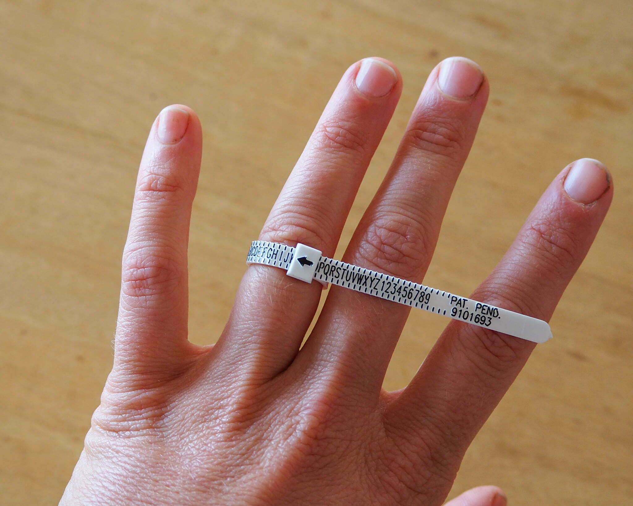 Hand wearing a ziptie-like ring sizing kit.