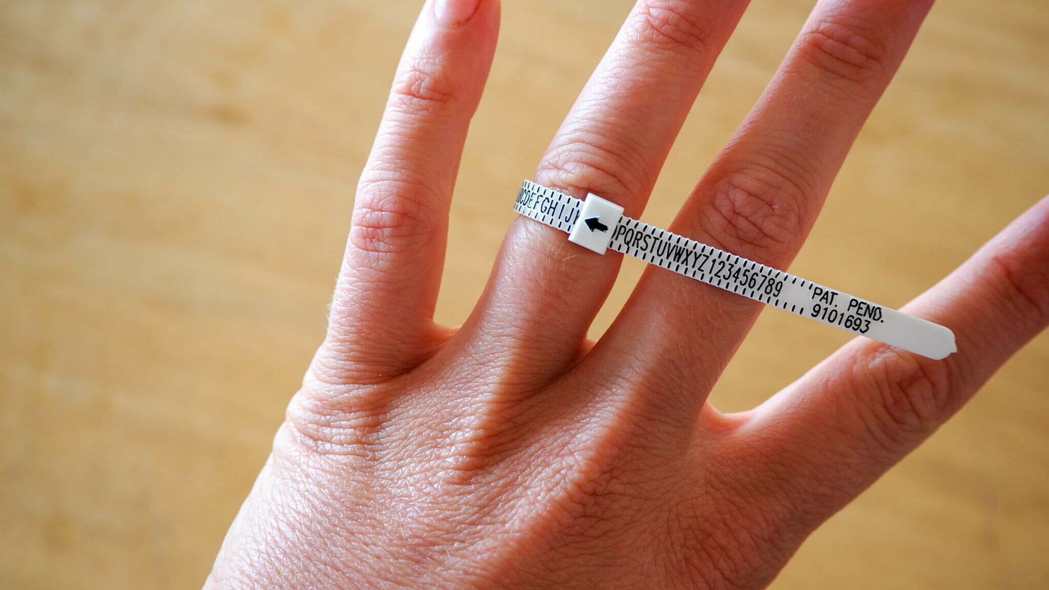 Hand wearing a ziptie-like ring sizing kit