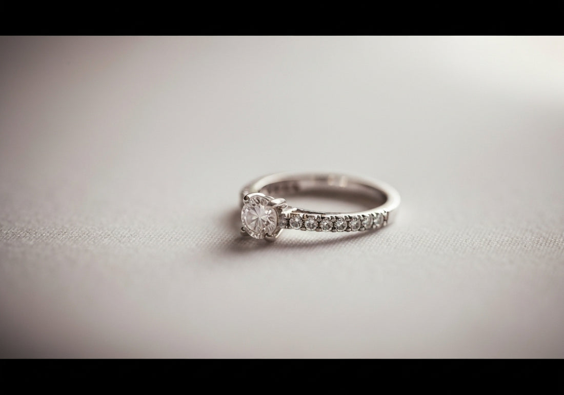A close-up view of a sparkling wedding ring on a soft, light fabric, illuminated by gentle natural light.