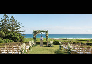 A picturesque outdoor wedding venue on the Sunshine Coast with a floral arch, ocean views, and lush greenery.
