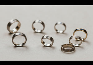 A selection of men's wedding rings in various styles and metals, representing diverse religious and cultural influences, displayed elegantly on a neutral background.