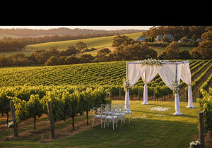 A stunning outdoor wedding setup in a Barossa Valley vineyard with lush green vines, rolling hills, and elegant decorations under golden sunlight.