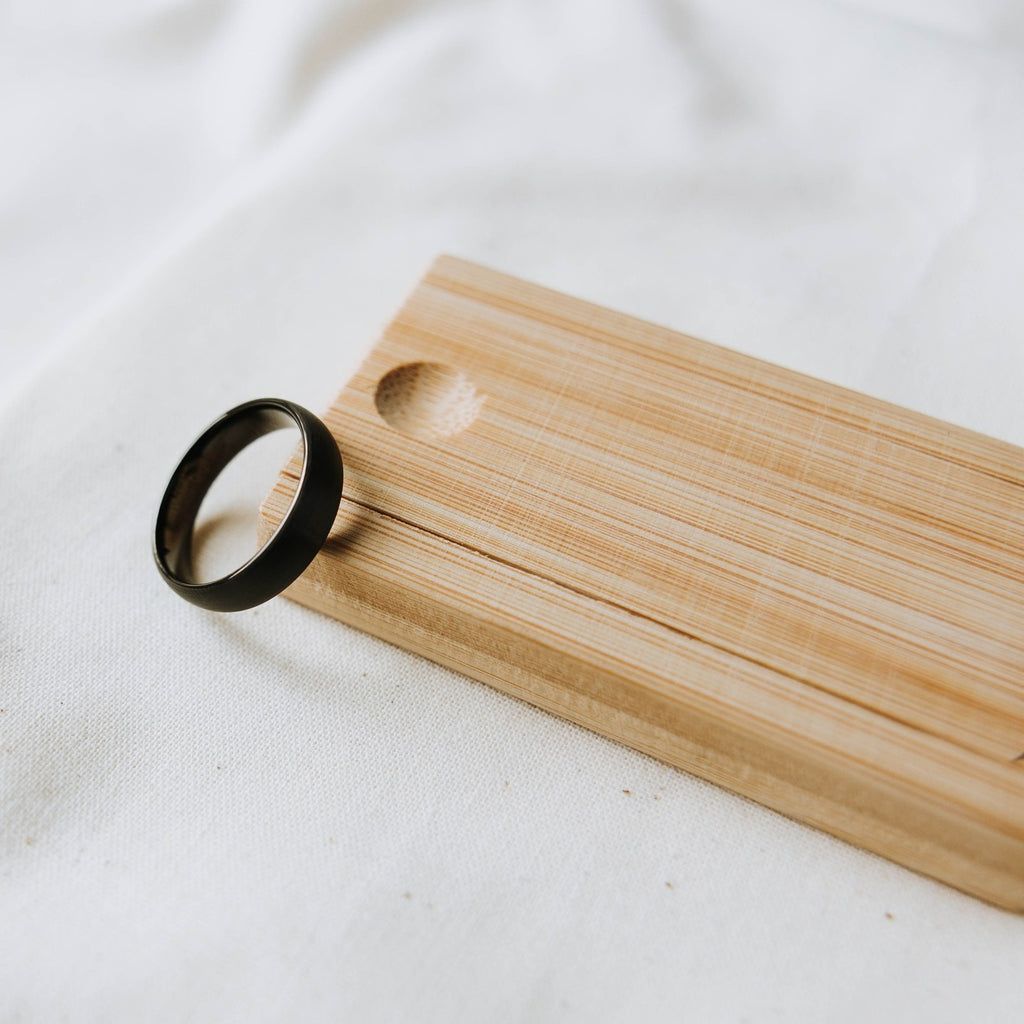 Black ring on a wooden ring box on a white background