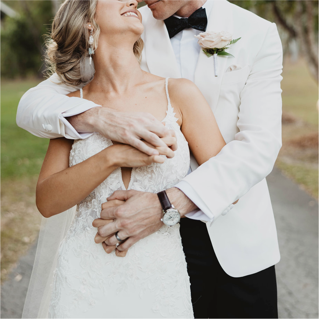 Couple embracing outdoors on their wedding day.