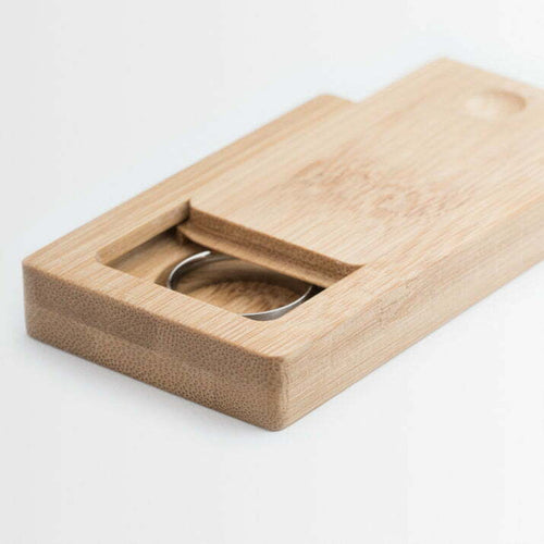 Wooden ring box with a silver ring inside on a white background
