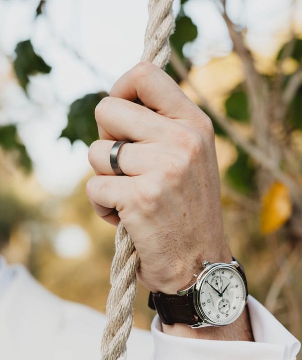 Man holding rope showing off his durable tungsten wedding ring.